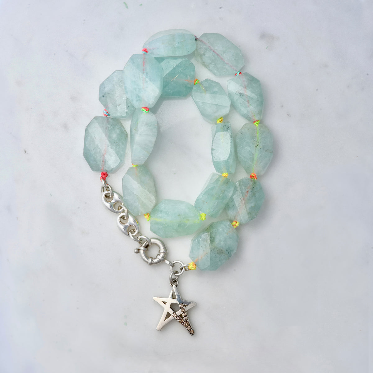 Aquamarine beads knotted on multicolored silk with a sterling silver star adorned with champagne diamonds.